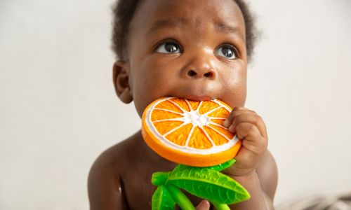 Kind hält Beißspielzeug aus Naturkautschuk in der Hand, Schadstofffreies Spielzeug von Oli&Carol kaufen
