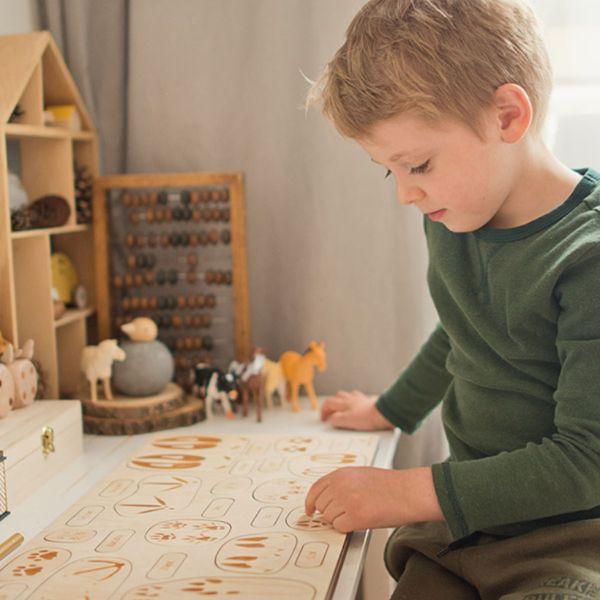 Kind spielt mit Holzpuzzle von Stuka Puka, Zuhause spielerisch lernen über Tiere und Pflanzenwelt, Freilernen Material Ökologisch