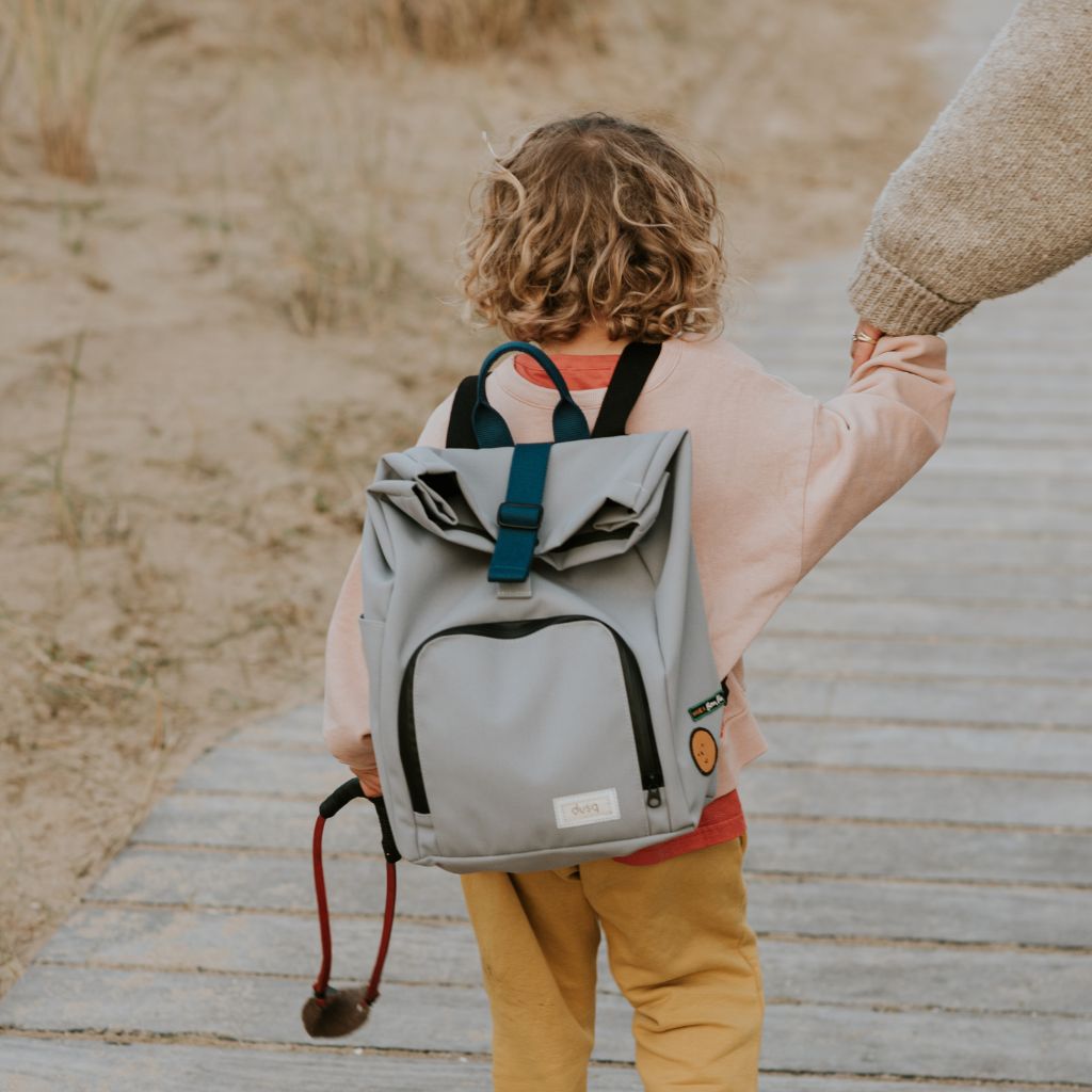 kind bei strandspaziergang, elternteil an der hand, mit nachhaltigem kinderrucksack von dusq