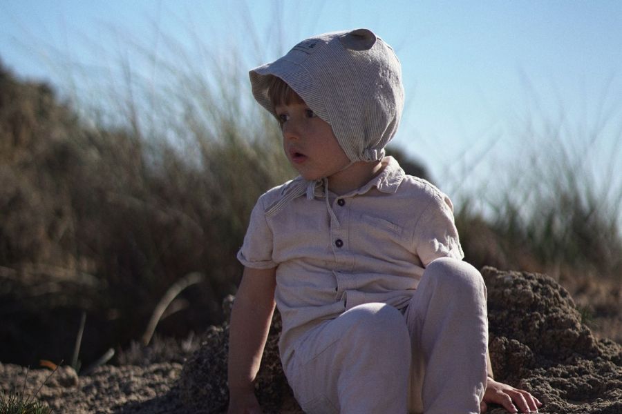 kind mit sonnenhut bonnet aus leinen am strand