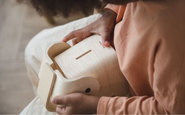 Kind hält Elefanten - Sparbüchse aus Holz in der Hand - Plantoys bei green and grow