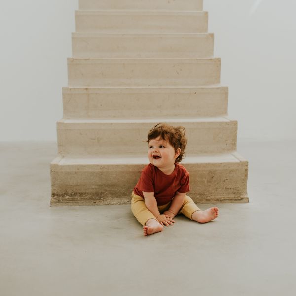 Kind sitzt vor Treppe, stylish gekleidet in Dusq