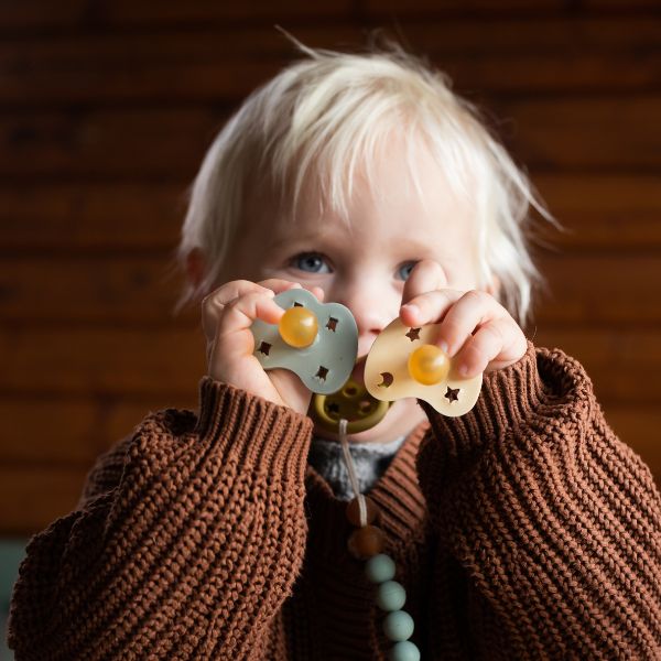 Kind in Strickpullover mit Schnuller und Schnullerketten aus Naturkautschuk von Hevea