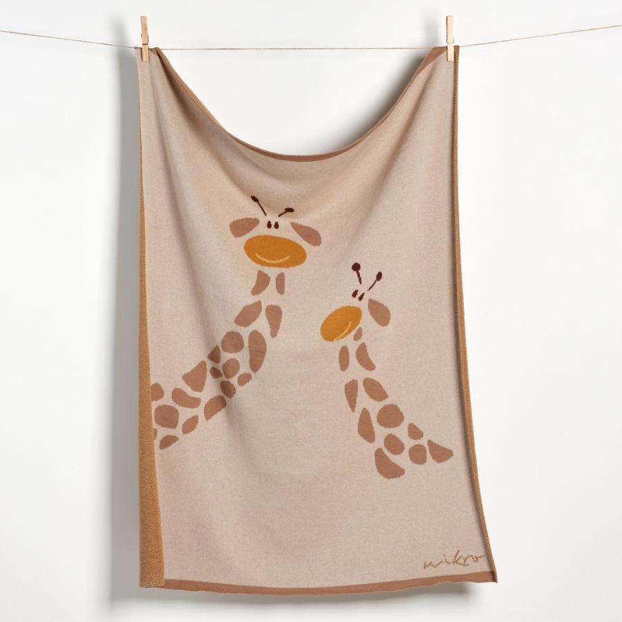 Beige Kuscheldecke aus Biobaumwolle mit Giraffenprint an Wäscheleine aufgehängt. 