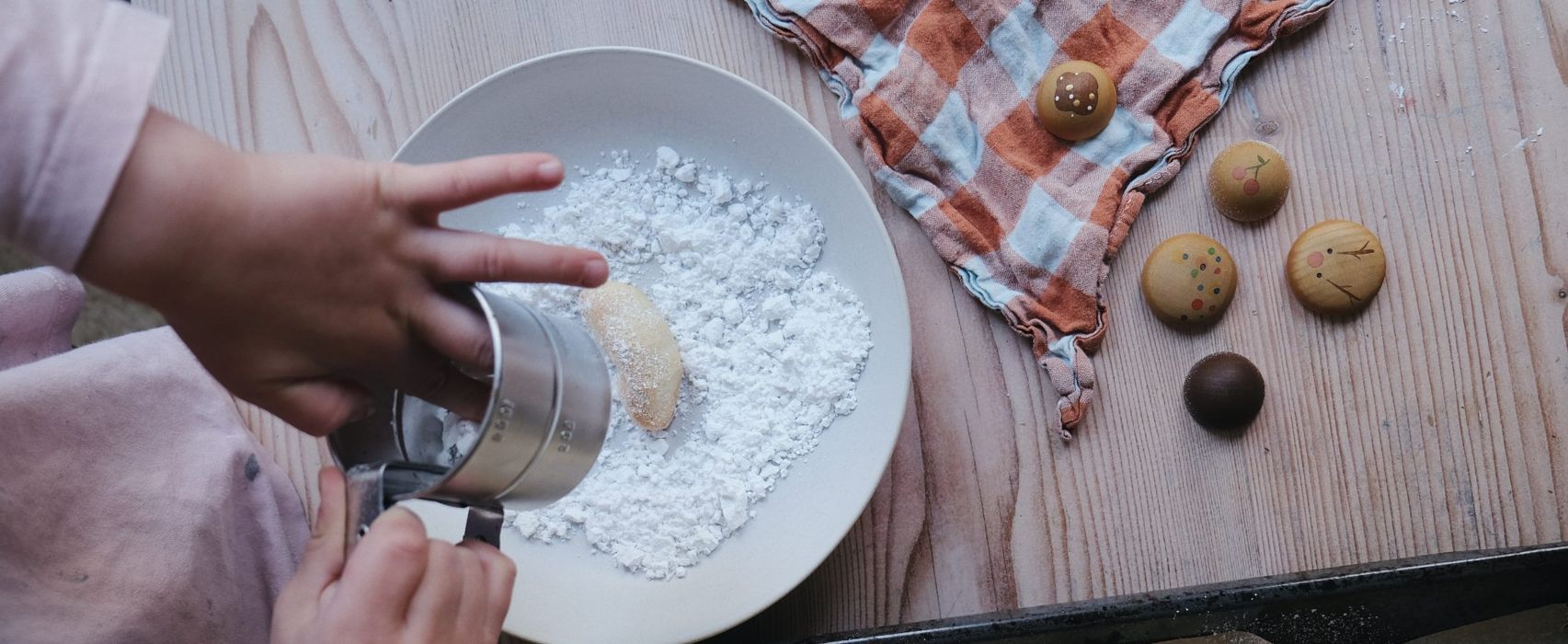 Kind backt, im Hintergrund freies Spielmaterial aus dem Grapat Adventkalender