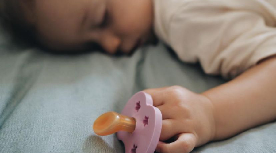 Baby schläft mit Latex-Schnuller in der Hand; Kiefergerechter Schnuller ohne Schadstoffe aus Latex