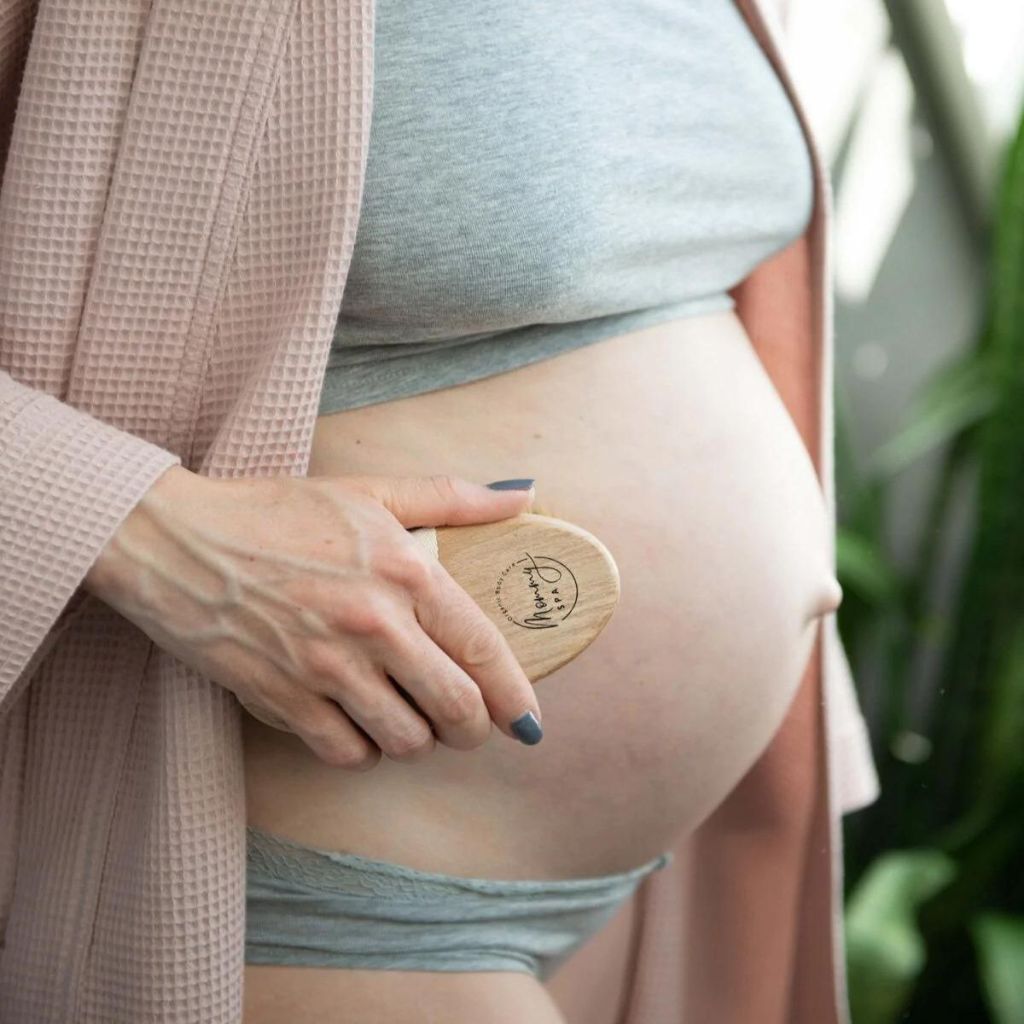 frau pflegt schwangerschaftsbauch mit bürstenmassage, natürliche schwangerschaftspflege plastikfrei vegan mommy spa 