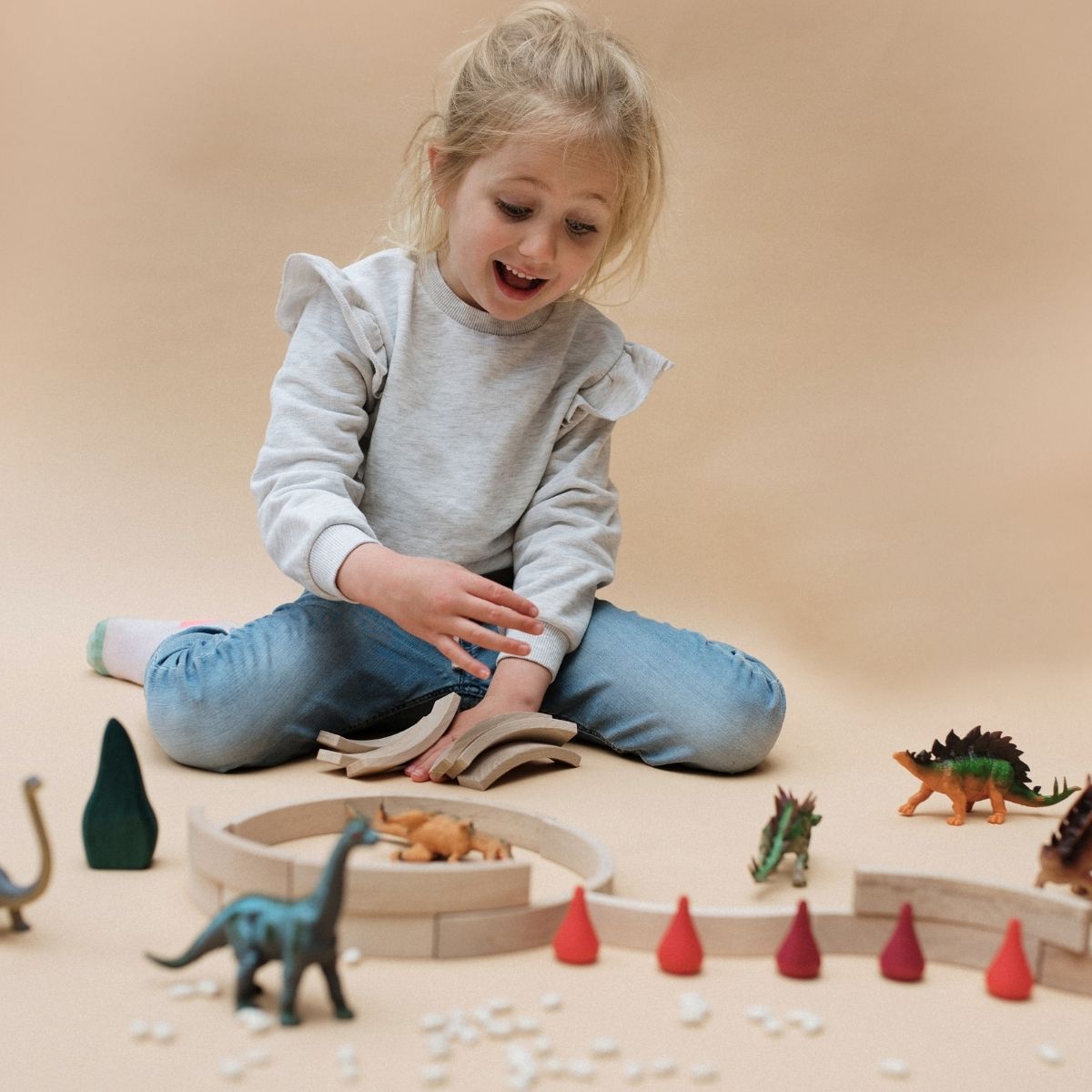 Kind spielt mit Abel Holzbausteinen und Dinosauriern